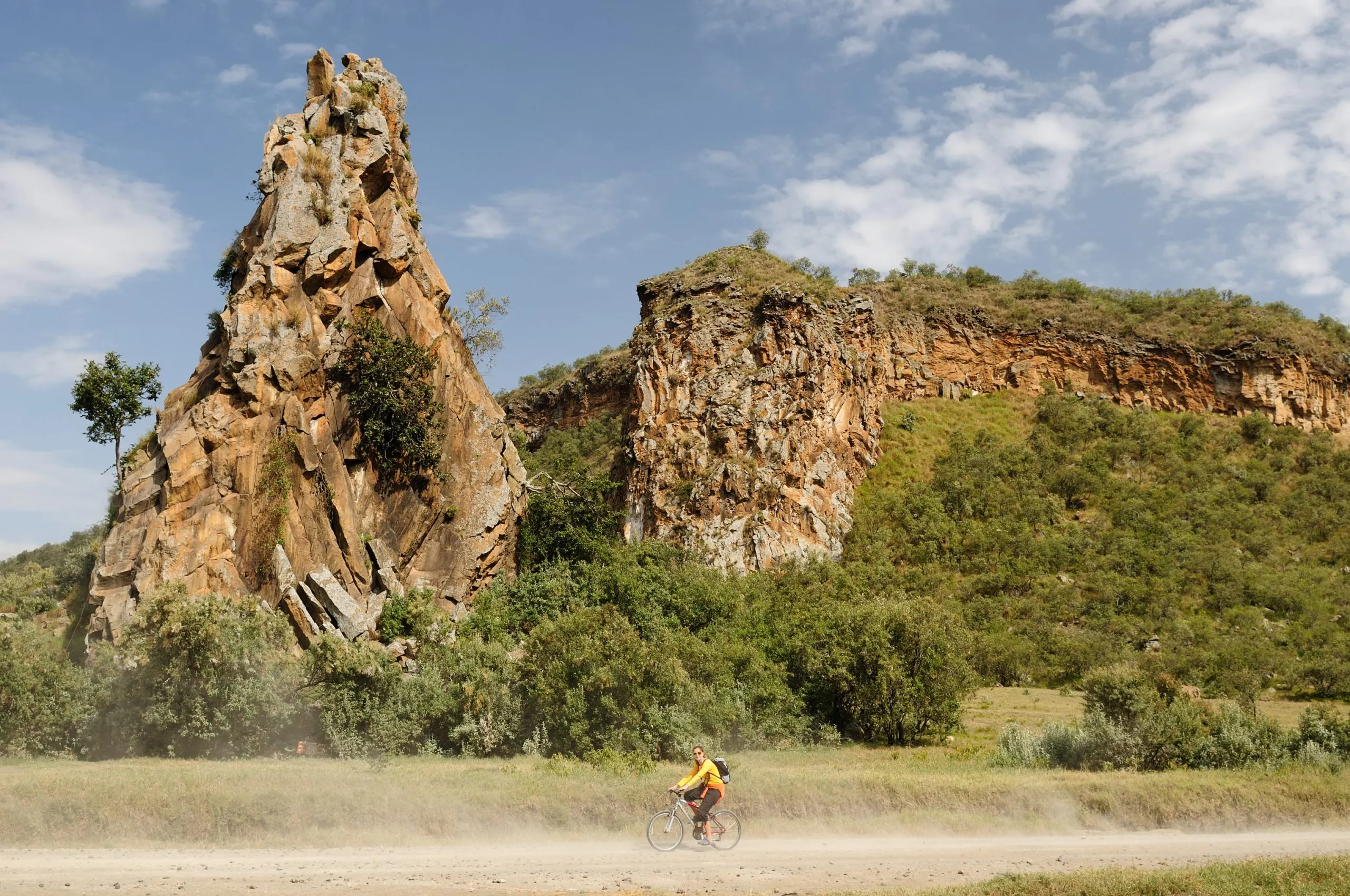 Der Tourist radelt am Fuße der Stark-Felsentürme im Hells Gate National Park in Kenia