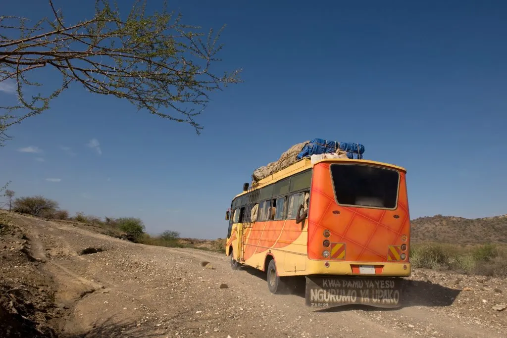 Rückansicht eines Busses, der auf einer unbefestigten Straße fährt, Tansania, Afrika