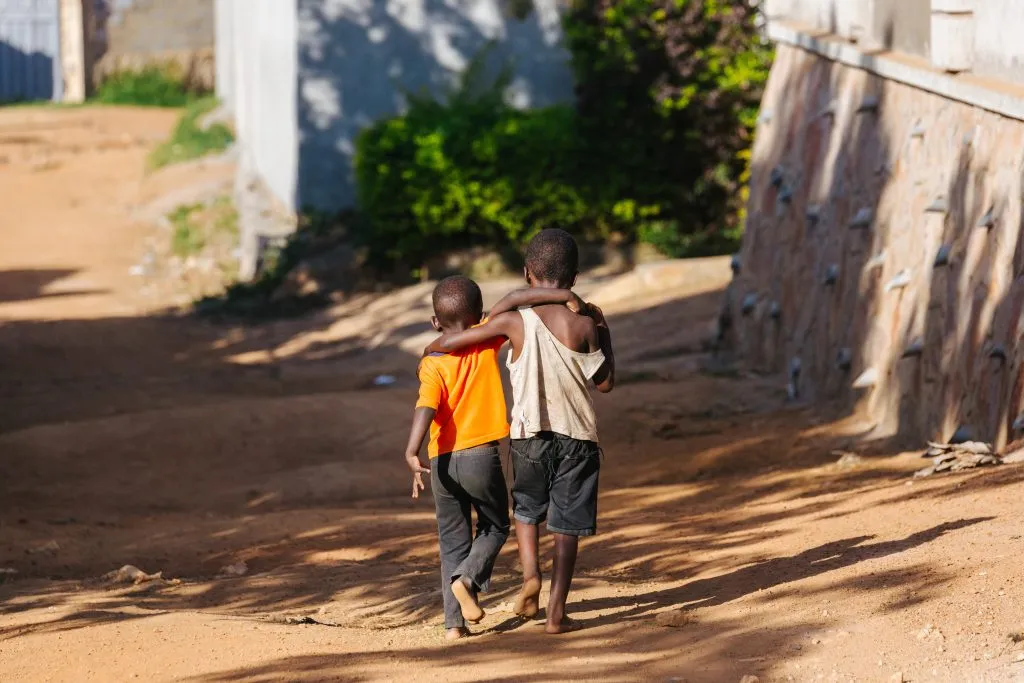jongens lopen arm in arm in Oeganda, Afrika
